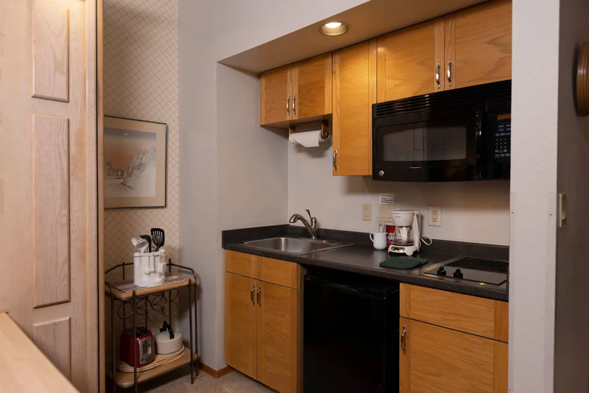 The photo highlights the kitchen area, featuring upper and lower cabinets, a sink, microwave, and a coffee maker on the counter. The inviting and practical setup suggests readiness for meal preparation, easy-access storage, and the pleasure of a fresh morning brew.